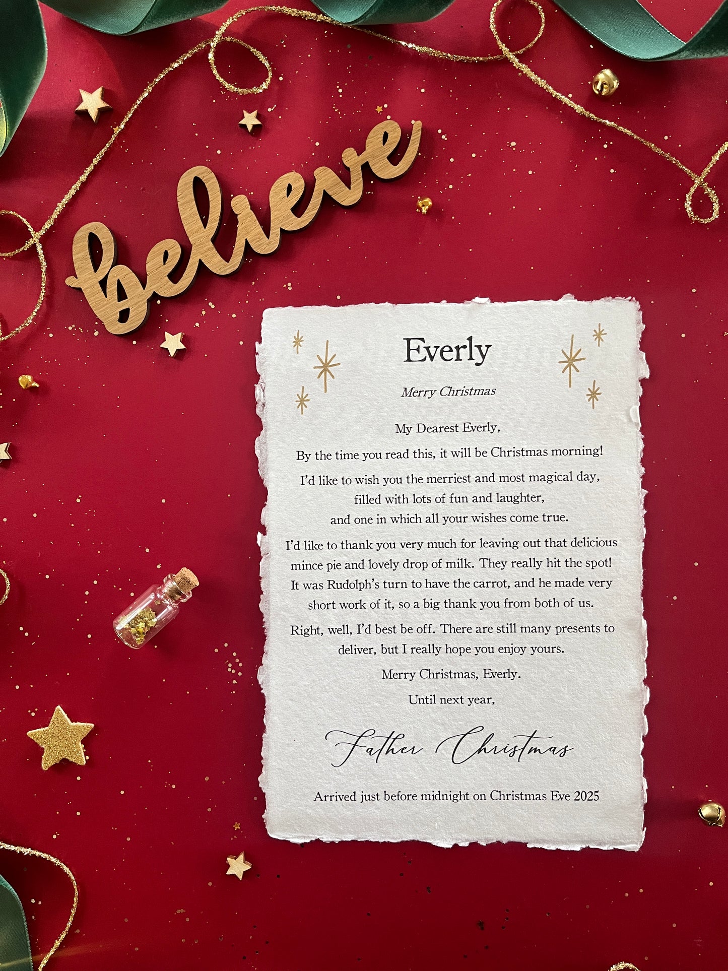 A Christmas morning letter which is entirely personalised with your child's names and unique to them. Finished with Golden stars and details of your Christmas Eve treats for Father Christmas or Santa Claus.
The note, printed on handmade paper, is pictured against a red background with magical decorations.